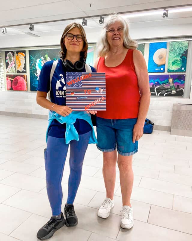 Host mother and AYA student holding a welcome sign.